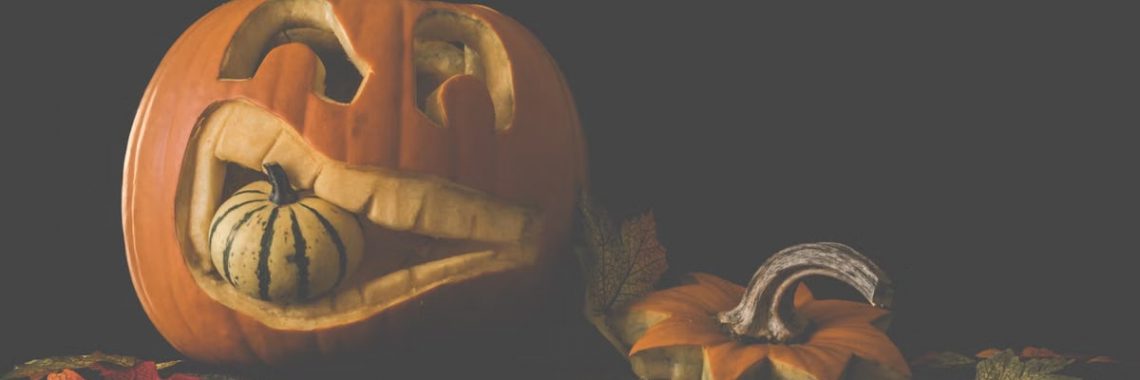 Carved jack-o'-lantern with a gourd and autumn leaves. Perfect for Halloween decor.